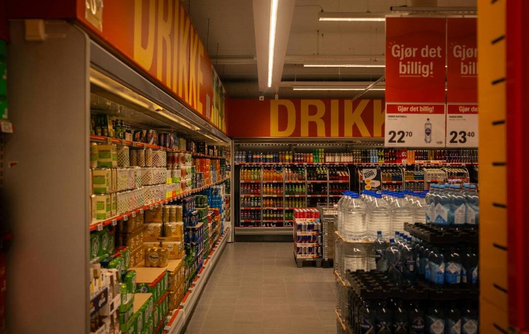Retail store cleaning in a stocked beverage aisle with refrigerated drinks and bottled water